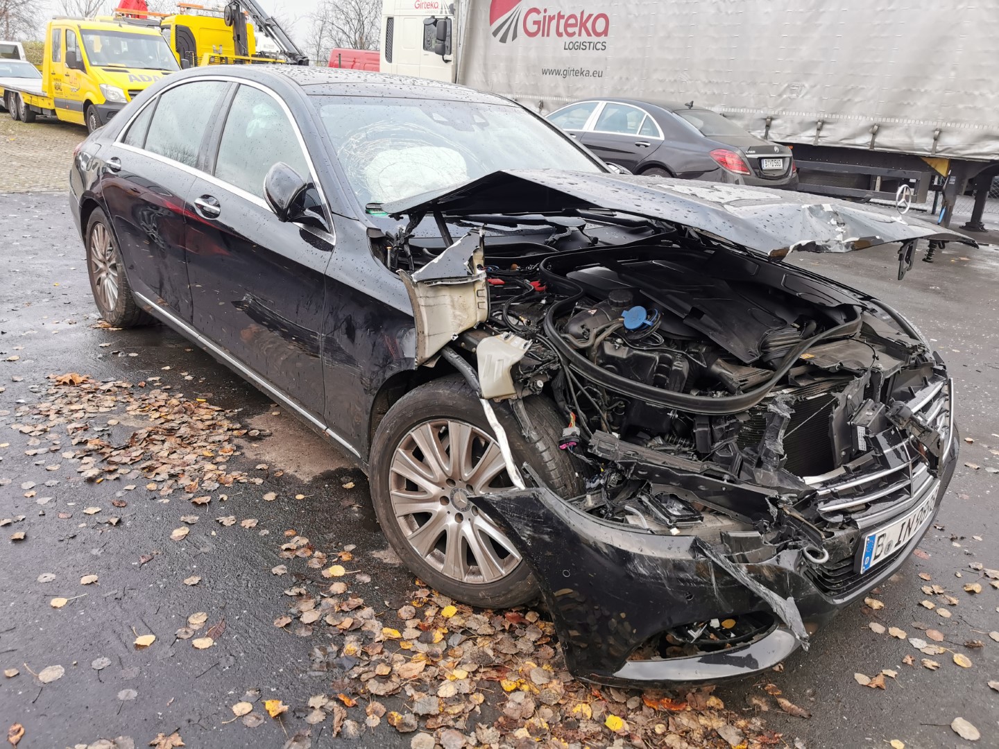 Ein stark beschädigtes schwarzes Auto mit deutlichen Unfallspuren am vorderen rechten Bereich.